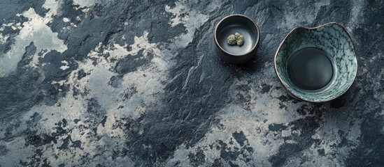 Poster - Bird's eye view of stone crockery featuring a stunning Silver Sapphire glaze in shades of blue and gray on a textured dark surface with two bowls.