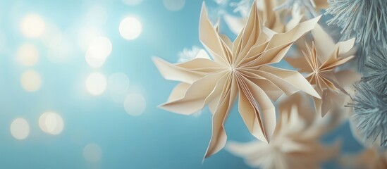Poster - Christmas paper decorations in soft pastel beige against a softly blurred blue background with bokeh effect creating a festive holiday atmosphere