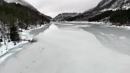 Wall Mural - Drone view of melt water covers the ice on lake Haugavatnet with snowy mountains and misty sky