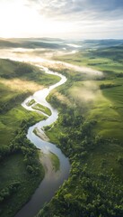 Poster - A serene aerial view of a winding river snaking through lush green fields, with soft mist rolling over the landscape under the first light of day