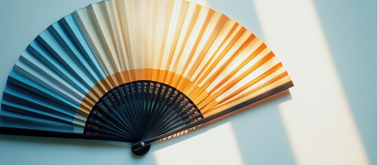Poster - Colorful fan with gradient hues from blue to orange, positioned diagonally against a light background casting soft shadows.