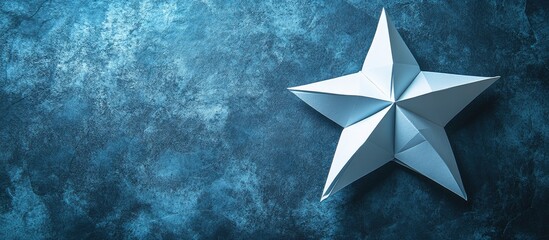 Poster - Five pointed origami star in white positioned top left on textured blue background creating a contrast between light and dark shades.