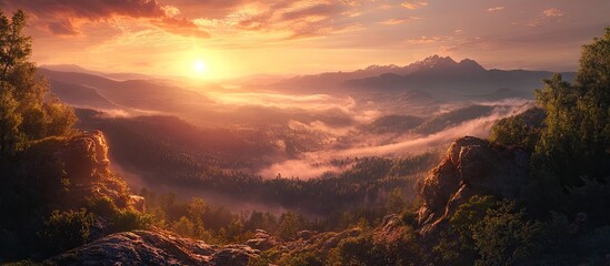 Poster - Serene sunset over fog-covered forested hills with warm orange, purple, and pink hues illuminating the landscape and rocky foreground elements.