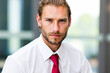 © Minerva Studio - Portrait of businessman wearing white shirt and red tie looking serious