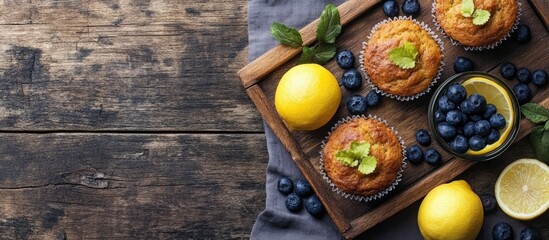 Sticker - Rustic wooden tray with fresh baked muffins blueberries verbena drink and lemons on coffee table empty space for text