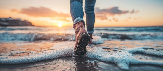 Wall Mural - Woman walking on beach at sunset with waves gently washing over her feet serene landscape with empty space for text