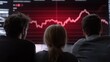 © Lifestyle Images - Three people, two men and a woman, sitting in front of a large screen with a red line graph on it. the line graph appears to be showing a downward trend, indicating a decrease in the stock market.