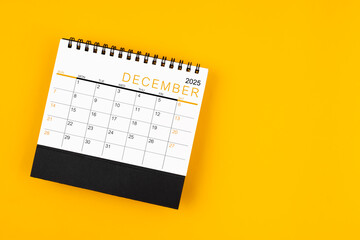 Wall Mural - December 2025 desk calendar on yellow background, position with copy space.