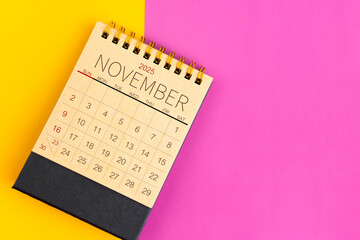 Wall Mural - November 2025 desk calendar made from brown paper page on multicolor background.