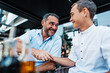 © Dusko - Handsome and happy father and his teenage son sitting in a restaurant and talking.