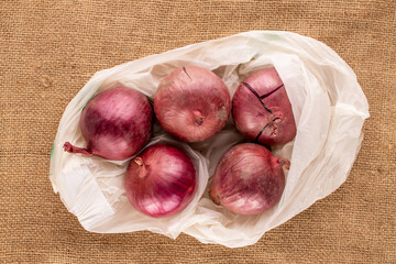 Wall Mural - Several blue onions in an organic bag on a jute cloth, top view, macro