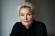 © songsi - Elegant and Thoughtful Middle-Aged Woman with Blonde Hair Posing in Soft Natural Light at Home