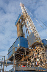 Wall Mural - Industrial winter landscape featuring an operational drilling rig with support facilities at a remote worksite during daylight hours