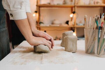 Poster - Potter is sculpting wet clay for ceramics products. Hands of a female potter making ceramic clay product on the table in the pottery workshop.