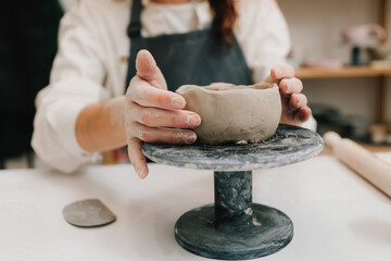 Poster - Process of creating ceramic products. Female potter hands shows ceramic bowl ready for firing in a kiln.