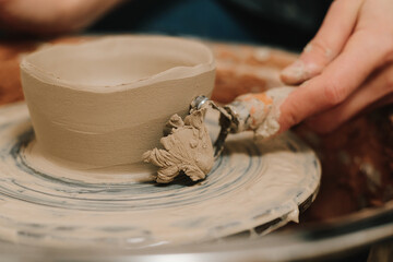 Fototapete - Creating ceramic earthenware on the manufacturing. Artisan forms clay pot with potters tool on the spinning wheel.
