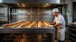 © Igor - A baker takes bread out of the oven in a bakery