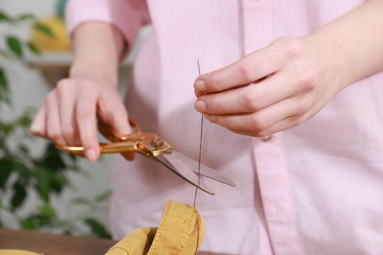 Wall Mural -  - woman sewing shirt with needle and thread indoors, closeup