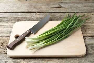 Wall Mural - Cutting board, green onions and knife on wooden table