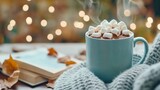 Cozy autumn day hot cocoa with marshmallows, book, sweater