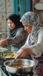 © liliyabatyrova - Two women in headscarves joyfully collaborate in a warm kitchen, skillfully cooking traditional meals filled with fresh ingredients and rich flavors. Their laughter and teamwork fill the air