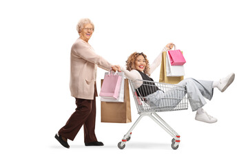 Canvas Print - Elderly woman pushing a young asian woman with shopping bags inside a shopping cart