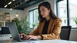 © Ada - Young professional it specialist latin hispanic business lady working on laptop pc sitting at desk in modern office space. 30s middle eastern indian woman using computer technology app for work online