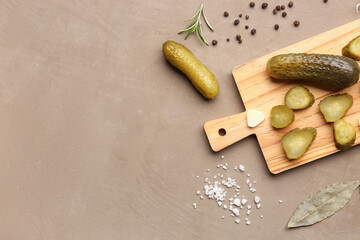 Wall Mural - Wooden board with pickled cucumbers and different spices on brown background