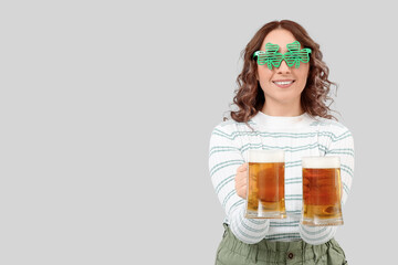 Wall Mural - Happy woman with beer celebrating St. Patrick's Day on light background