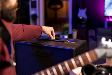 Leinwandbilder - Sound engineer adjusting volume levels on his amplifier to record acoustic guitar tunes for editing session in music post production. Male producer composing a new song in home studio. Close up.