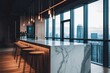 © BerkahStock - Modern office kitchen with marble countertop, bar stools, and panoramic city view.