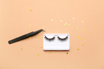 Wall Mural - False eyelashes with tweezers and sequins on beige background