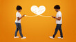 © Prostock-studio - A couple expresses affection while standing apart, using smartphones to connect. The warm orange background enhances the heart symbol, representing their online love celebration on St.