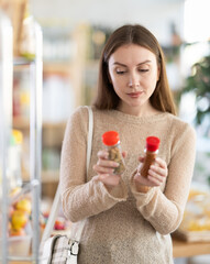 Wall Mural - Young woman buyer chooses spices and seasonings in jar in grocery store