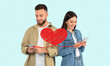 © Prostock-studio - A couple stands together while using their smartphones to exchange affectionate messages. They celebrate St. Valentines Day, sharing smiles and love online, isolated against a light background.