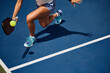 © joescarnici - Legs and shadow of a girl playing pickleball on a blue court