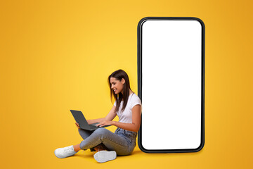 Wall Mural - people and technology. smiling woman using and looking at pc screen, sitting and leaning on big smar