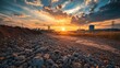 © Natchooda - An industrial site bathed in the glow of sunset, with rocky ground in the foreground, showcasing a dramatic landscape of work and nature under a colorful sky