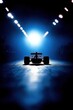© Nayotsaphon - A sleek racing car is illuminated from behind in a dark setting, creating a dramatic silhouette against a bright blue light.