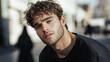 © Sum - Intriguing Gaze: A young man with tousled brown hair and a well-groomed beard, captivating with his intense gaze. The slightly blurred urban background adds an air of mystery.