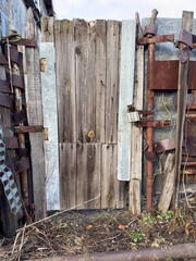 Wall Mural - A wooden door with a rusty gate is in front of a building