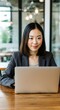 © Anna - Businesswoman smiling while working on laptop in modern office environment