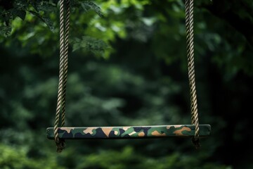 Poster - Camouflage swing hangs in front of a blurred green background