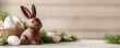 © Y_Malashkevych - A delightful chocolate bunny sits serenely on a rustic table surrounded by colorful Easter eggs and soft greenery under a gentle blur of light that creates a festive atmosphere