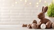 © Y_Malashkevych - A delightful chocolate bunny captures attention on a rustic table surrounded by various Easter eggs. The soft blurred background creates a warm festive atmosphere for the celebration