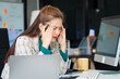 © Phushutter - Asian businesswoman sits at her ergonomic desk, working on a laptop and mobile phone. Her posture ensures minimal strain, addressing neck pain, back pain, and preventing repetitive strain injuries.