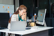 © Phushutter - Asian businesswoman sits at her ergonomic desk, working on a laptop and mobile phone. Her posture ensures minimal strain, addressing neck pain, back pain, and preventing repetitive strain injuries.
