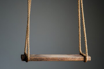 Poster - Simple wooden swing hangs suspended against a muted gray backdrop