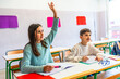 © unai - Elementary school student raising hand in classroom to answer question
