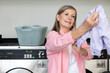 © zinkevych - Mature caucasian woman in pink tshirt holding in hands fresh clean clothes
